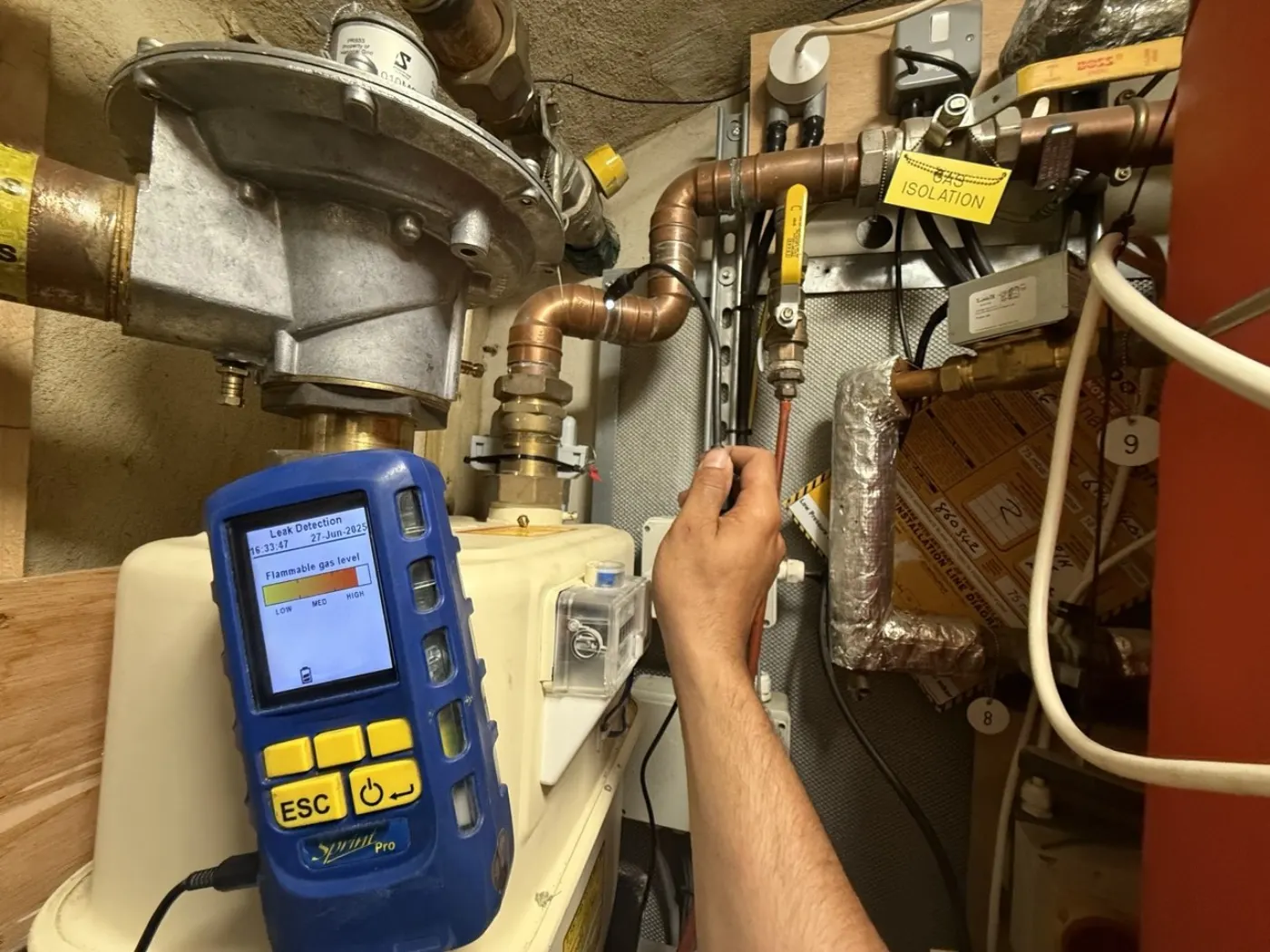 Gas Safe engineer using an electronic gas leak detector at a London gas meter