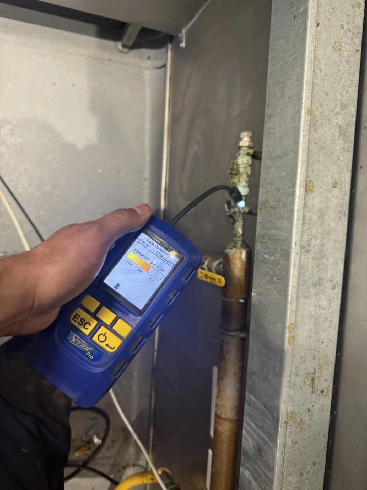 Engineer using handheld electronic acoustic leak detector on copper pipework